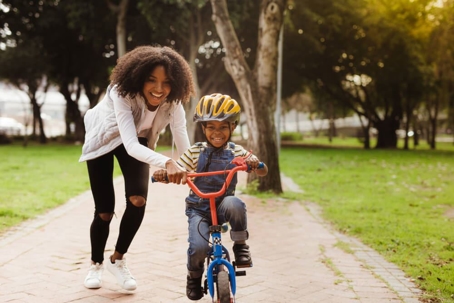 Happy cute boy learn to ride a bike with his mother.